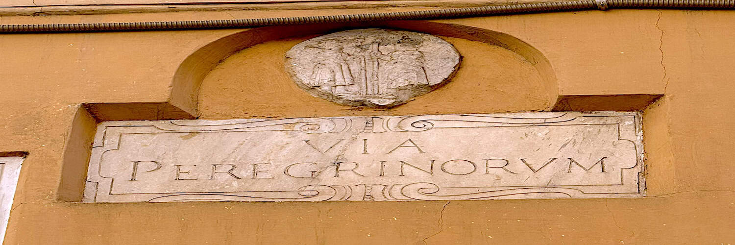 Iscrizione antica su muro con scritta "Via Peregrino" e stemma scolpito in rilievo