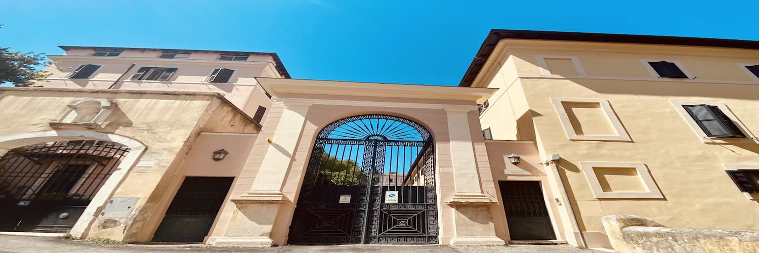 Ingresso di palazzo storico romano con arco e cancello in ferro battuto